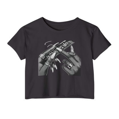 Women's cropped t-shirt with bold graphic of manicured hands rolling a blunt, raw hem edges, and relaxed fit.